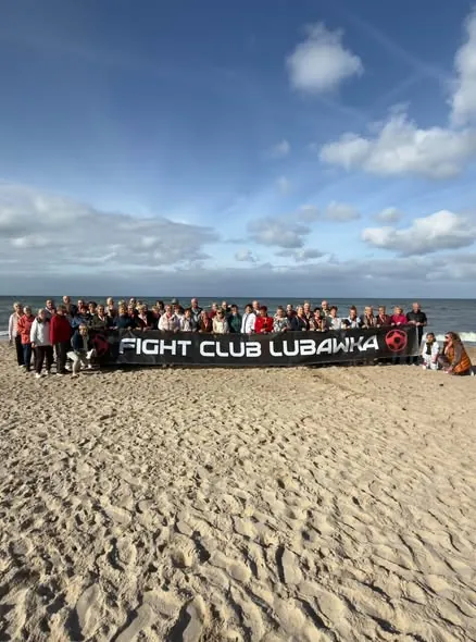 Grupa seniorów z banerem Fight Club Lubawka na plaży w Pobierowie